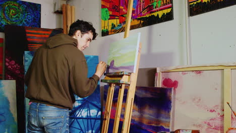 Young-Handsome-Painter-Working-In-The-Studio-Draws-A-Typical-American-Rural-Landscape