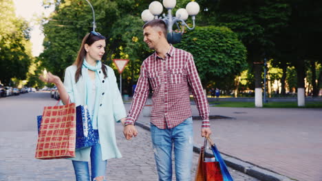 Young-Couple-Walking-Through-The-City-With-Shopping-Bags-They-Are-Happy-Smiling-Talking