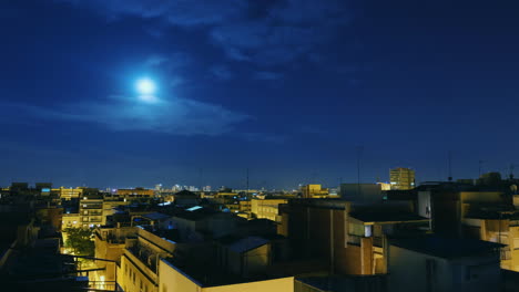 Moonrise-Over-The-City-And-The-Roofs-Of-Houses-Timelapse-From-Evening-To-Dawn-The-Sun-Rises-Over-The