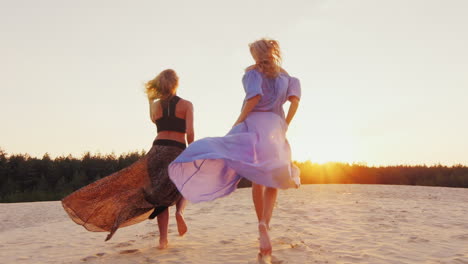 Two-Women-In-Light-Dresses-Run-Toward-The-Sun-Concept-Women's-Dreams-Health-Happiness-Steadicam-Slow