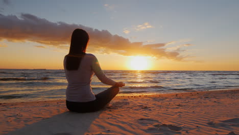 No-Stress-Calm-Young-Woman-Sitting-In-A-Lotus-Position-On-The-Beach-At-Sunset