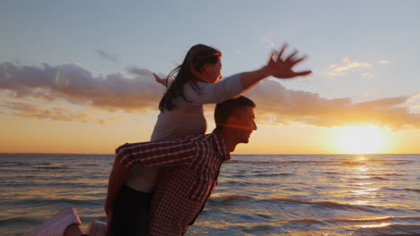 Young-Couple-In-Love-Having-Fun-On-The-Beach-At-Sunset-Berugi-A-Girl-Sits-On-The-Shoulders-Of-Men-Ru