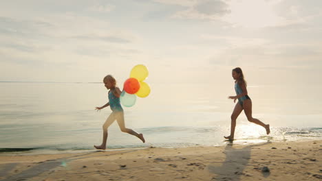 Two-Girls-Laughing-Together-Playing-On-The-Beach-Catching-Up-With-Each-Other-Holding-Balloons