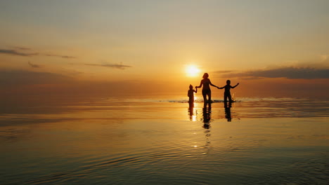 Mother-With-Two-Children-Laughing-In-The-Sea-At-Sunset-Out-Of-The-Water