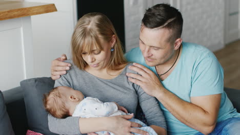 Young-Couple-Resting-At-Home-With-The-Baby-In-Her-Arms