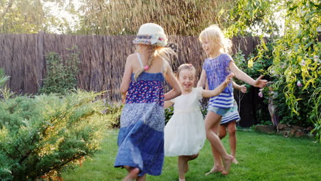 Four-Carefree-Children-Laughing-In-Garden-During-With-Streams-Of-Water