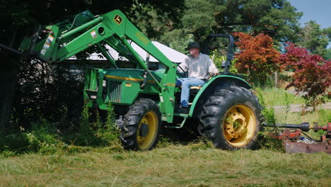 A-Man-On-A-Tractor-Mows-Tall-Grass-In-The-Yard