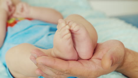 An-Adult-Male-Hand-Holding-A-Small-Baby-Feet-The-Concept---Care-And-Protection-Of-Parents-And-Happy-