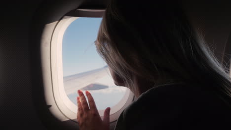Silhouette-Of-A-Woman-Looks-Out-The-Porthole-At-The-Sky-And-The-Wing-Of-The-Plane-In-Flight-Enjoy-Th