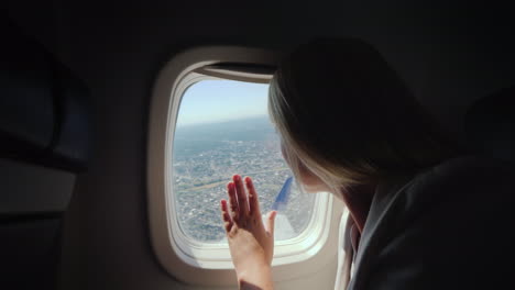 A-Female-Passenger-Looks-Out-The-Window-Of-The-Airliner-To-The-Ground-Below-Where-The-Big-Metropolis