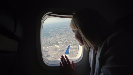 A-Female-Passenger-Looks-Out-The-Window-Of-The-Airliner-To-The-Ground-Below-Where-The-Big-Metropolis