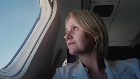 Portrait-Of-A-Confident-Female-Passenger-Flying-In-An-Airplane-Looking-Out-The-Window