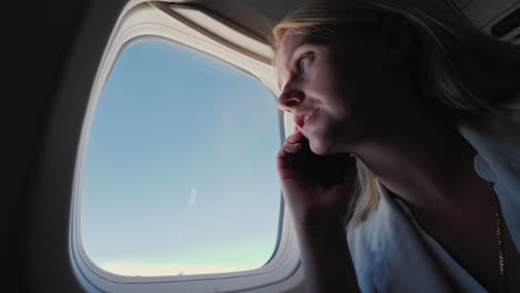 Business-Woman-Talking-On-The-Phone-In-The-Cabin-Of-An-Airliner