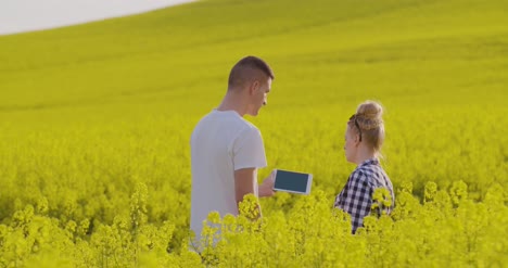 Farmers-Discussing-Over-Tablet-Computer-At-Rapeseed-Field-4