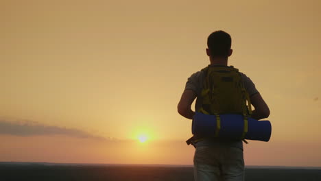 A-Young-Male-Tourist-With-A-Backpack-Looks-At-The-Horizon-Where-The-Sun-Sets-Back-View-4k-Video
