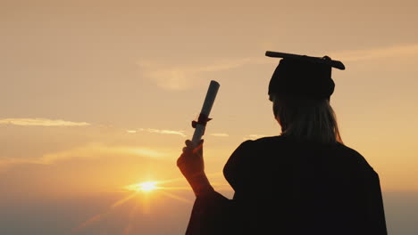 Graduate-With-A-Diploma-Looks-At-The-Sunrise-Over-The-Sea---Perspective-And-Inspiration-Concept