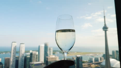 Hand-With-A-Glass-Of-Wine-Against-The-Background-Of-The-Window-Where-The-Famous-Cn-Tower-Of-Toronto-