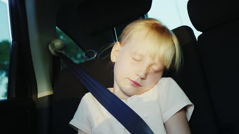 The-Girl-Is-6-Years-Old-Riding-In-The-Back-Seat-Of-The-Car-Buckled-With-A-Seat-Belt-And-Sleeps-On-Th