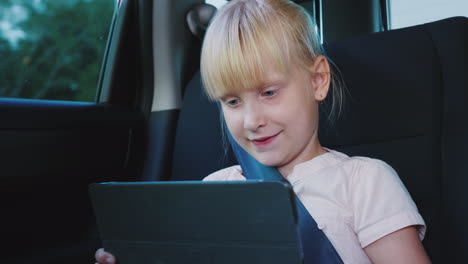 Fun-On-The-Road-The-Girl-Uses-A-Tablet-Rides-In-The-Back-Seat-Of-The-Car-4k-Video