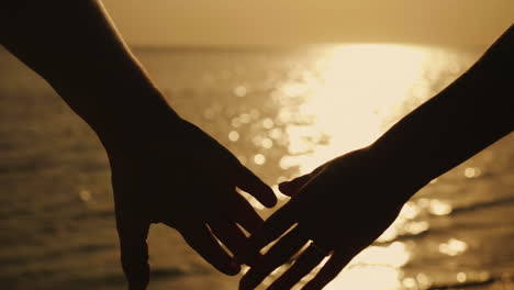 Hands-Of-A-Man-And-A-Woman-Against-The-Background-Of-The-Sea-And-The-Setting-Sun-4k-Slow-Motionvideo