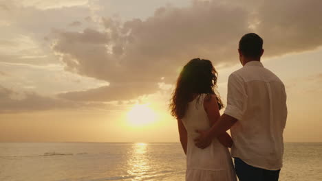 Young-Couple-In-Love-Embraces-Look-Together-Forward-To-The-Sunset-By-The-Sea-Back-View-Hd-Video