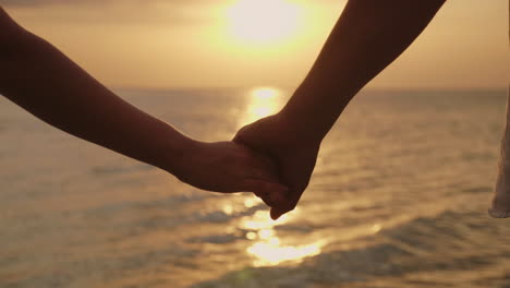 Hands-Of-A-Man-And-A-Woman-Against-The-Background-Of-The-Sea-And-The-Setting-Sun-4k-Slow-Motionvideo