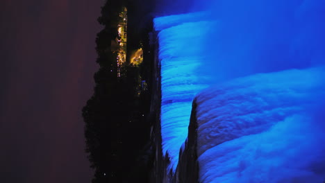 Vertikales-4k-Video---Nachtansicht-Von-Niagara-Falls-Wasserströmen,-Die-Von-Einem-Blauen-Flutlicht-4k-Video-Beleuchtet-Werden