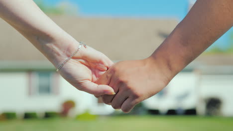 A-Young-Couple-Holding-Hands-Against-The-Backdrop-Of-Their-New-Home-Buying-Real-Estate-Concept-A-Dre