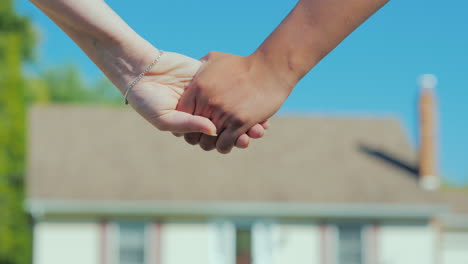 A-Young-Couple-Holding-Hands-Against-The-Backdrop-Of-Their-New-Home-Buying-Real-Estate-Concept-A-Dre