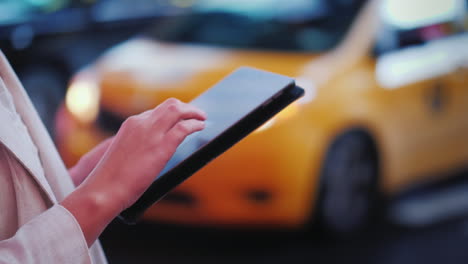 Verwenden-Sie-Das-Tablet-Auf-Einer-Belebten-Straße-In-New-York-Im-Hintergrund,-Vorbei-An-Den-Berühmten-Gelben-Taxis-In-Der-Nähe