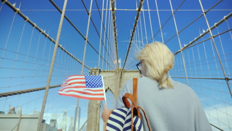 A-Woman-With-The-Flag-Of-America-In-Her-Hand-Is-On-The-Brooklyn-Bridge
