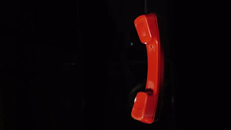 Roter-Telefonhörer-Von-Einem-Retro-Telefon,-Das-An-Einem-Draht-Auf-Schwarzem-Hintergrund-Hängt-4k-Video-Hanging