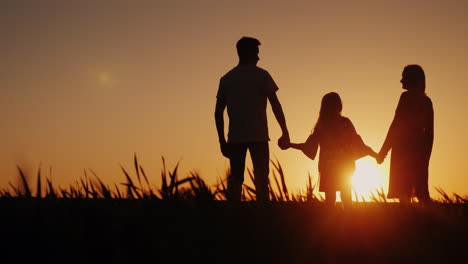 Eine-Dreiköpfige-Familie-Freut-Sich-Auf-Einen-Wunderschönen-Sonnenuntergang-4k-Video-Von-Hinten