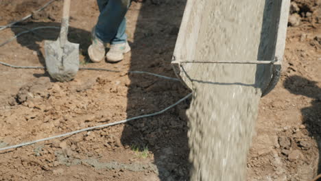 Pouring-Concrete-Into-The-Foundation-From-The-Gutter-Concrete-Flows-Next-To-The-Worker-With-A-Shovel