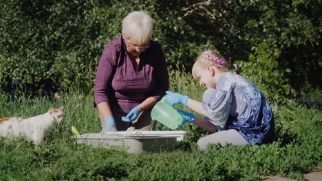 Grandmother-And-Granddaughter-Put-Flowers-Together-In-The-Yard-Active-Senior-People-Concept