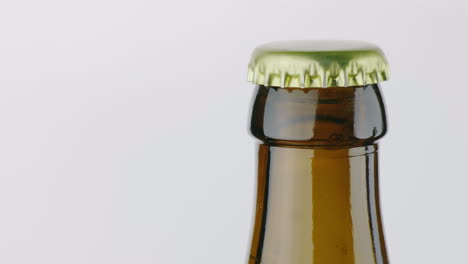 Der-Hals-Einer-Bierflasche-Ist-Mit-Einem-Metalldeckel-Auf-Weißem-Hintergrund-4k-Video-Bedeckt