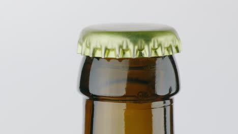 The-Neck-Of-A-Bottle-Of-Beer-Is-Covered-With-A-Metal-Lid-On-A-White-Background