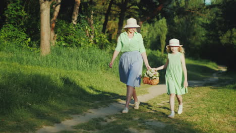 Mom-And-Daughter-Are-Walking-Along-A-Path-In-The-Forest-Carrying-A-Basket-With-Wildflowers-Happy-Par