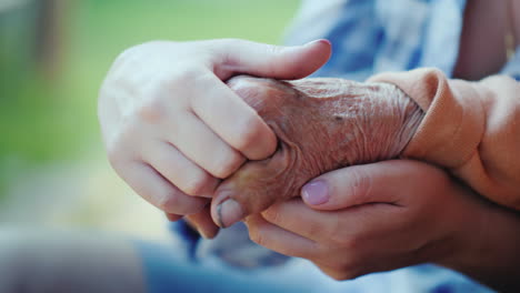 A-Young-Woman-Holds-An-Elderly-Lady\'s-Hand-Close-Up-Video