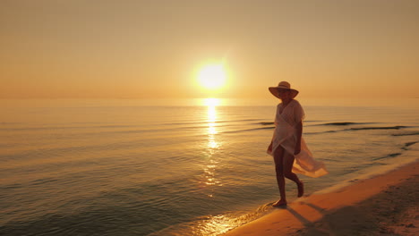 Woman-Tourist-Happily-Strolls-At-The-Water's-Edge-Near-The-Sea-At-Sunset
