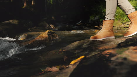 A-Traveler-In-Hiking-Boots-Passes-Through-Slippery-Stones-Only-The-Legs-Are-Visible