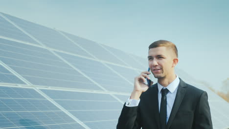 Successful-Businessman-Talking-On-The-Phone-On-The-Background-Of-A-Solar-Power-Station
