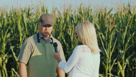 A-Journalist-Interviews-A-Successful-Farmer-Stand-In-The-Background-Of-A-Field-Of-Corn