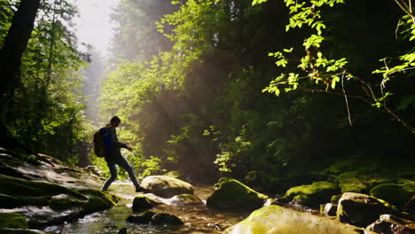 Silhouette-Eines-Mannes-Mit-Rucksack-überquert-Einen-Bergfluss-Oder-Einen-Schönen-Wald-Mit-Strahlen-Von