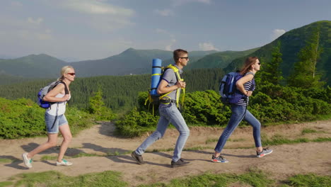 A-Group-Of-Tourists-Enjoy-A-Hike-In-The-Mountains-They-Go-On-A-Picturesque-Background-Of-Mountains-A