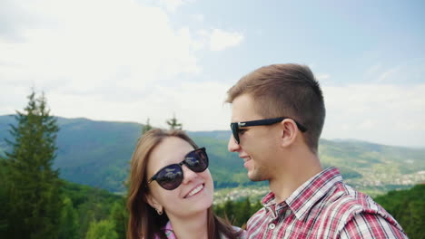 Young-Active-Couple-Taking-Pictures-Against-The-Backdrop-Of-A-Beautiful-Mountain-Landscape