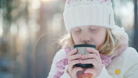 A-6-Year-Old-Girl-Drinks-Hot-Tea-On-The-Street-Against-The-Background-Of-The-Winter-Forest-Slow-Moti