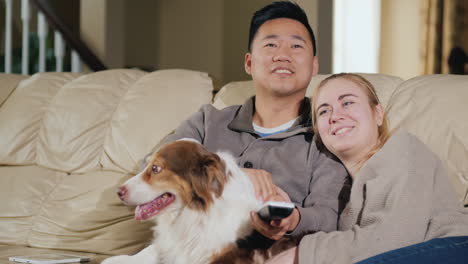 Young-Loving-Couple-With-Dog-Sit-On-The-Couch-Watching-Tv