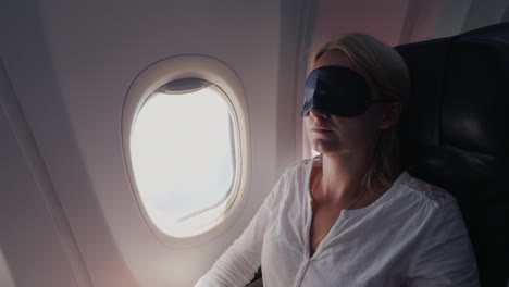A-Young-Woman-With-A-Dark-Bandage-In-Her-Eyes-Sleeps-In-The-Cabin-Of-A-Passenger-Aircraft-Traveling-