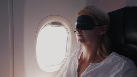 A-Young-Woman-With-A-Dark-Bandage-In-Her-Eyes-Sleeps-In-The-Cabin-Of-A-Passenger-Aircraft-Traveling-